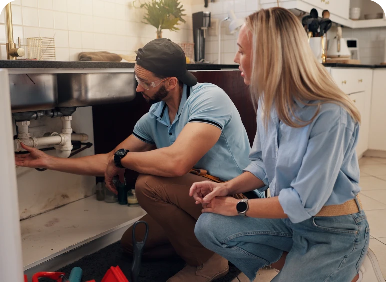Man and woman inspecting kitchen sink plumbing