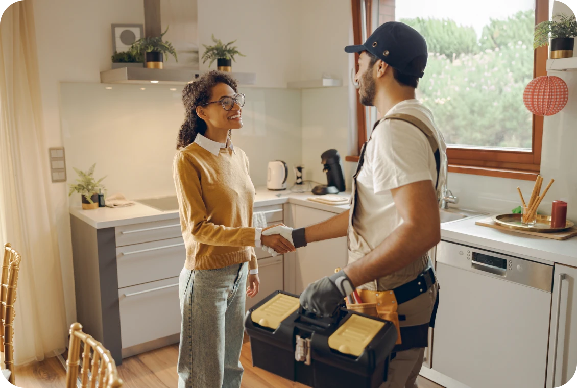 Smiling woman greeting repairman in cozy kitchen.